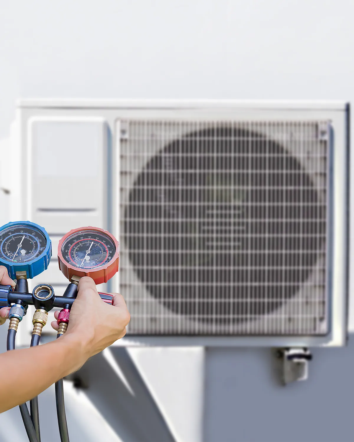 HVAC technician checking gauges on an outdoor condenser unit