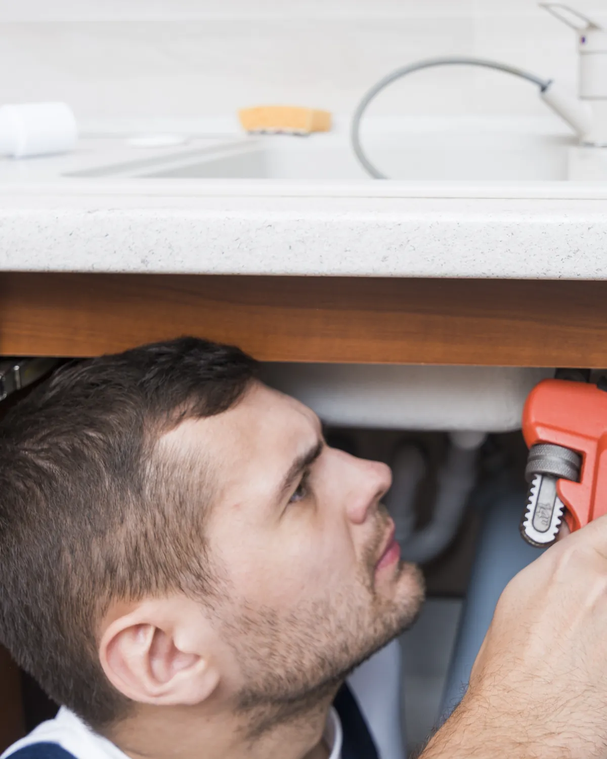 Plumber repairing a pipe under a kitchen sink