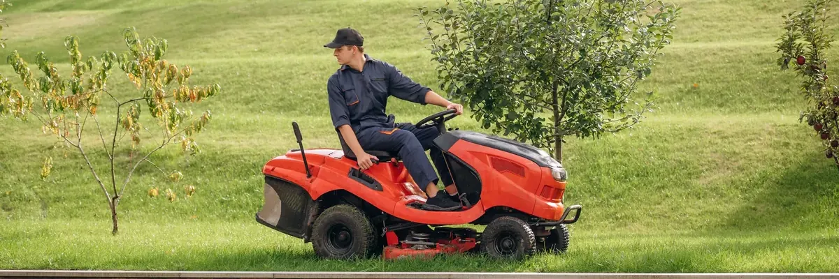 Landscaper mowing a lawn on a red ride-on mower